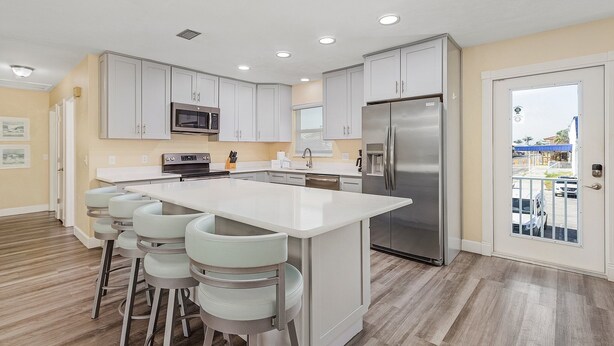 A modern kitchen with white cabinets, stainless steel appliances, and a central island with bar stools.