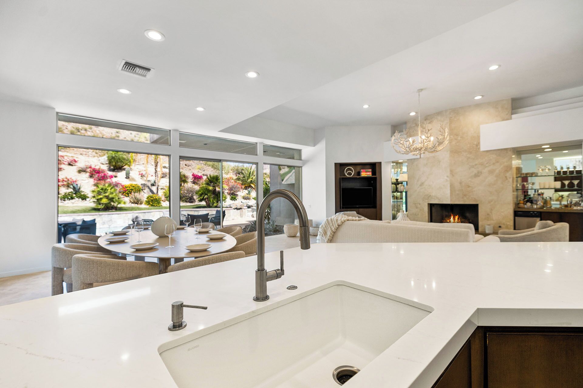 A modern kitchen with a large island, a dining area with a round table, and a living area with a fireplace.