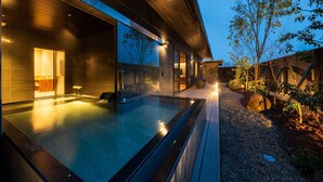 Ein modernes Gebäude mit einem großen Außenpool, einer Holzterrasse und einem gut beleuchteten Innenraum.