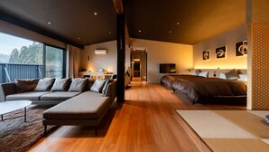 Ein modernes Hotelzimmer mit einem großen Bett, einer Sitzecke, einem Essbereich und Blick ins Freie.