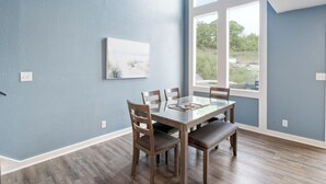 Une salle à manger avec une grande table, des chaises et une fenêtre donnant sur un paysage verdoyant.