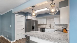 Een moderne keuken met witte kasten, een granieten aanrecht en roestvrijstalen apparatuur.