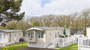 A row of mobile homes with a grassy yard and a wooden deck.