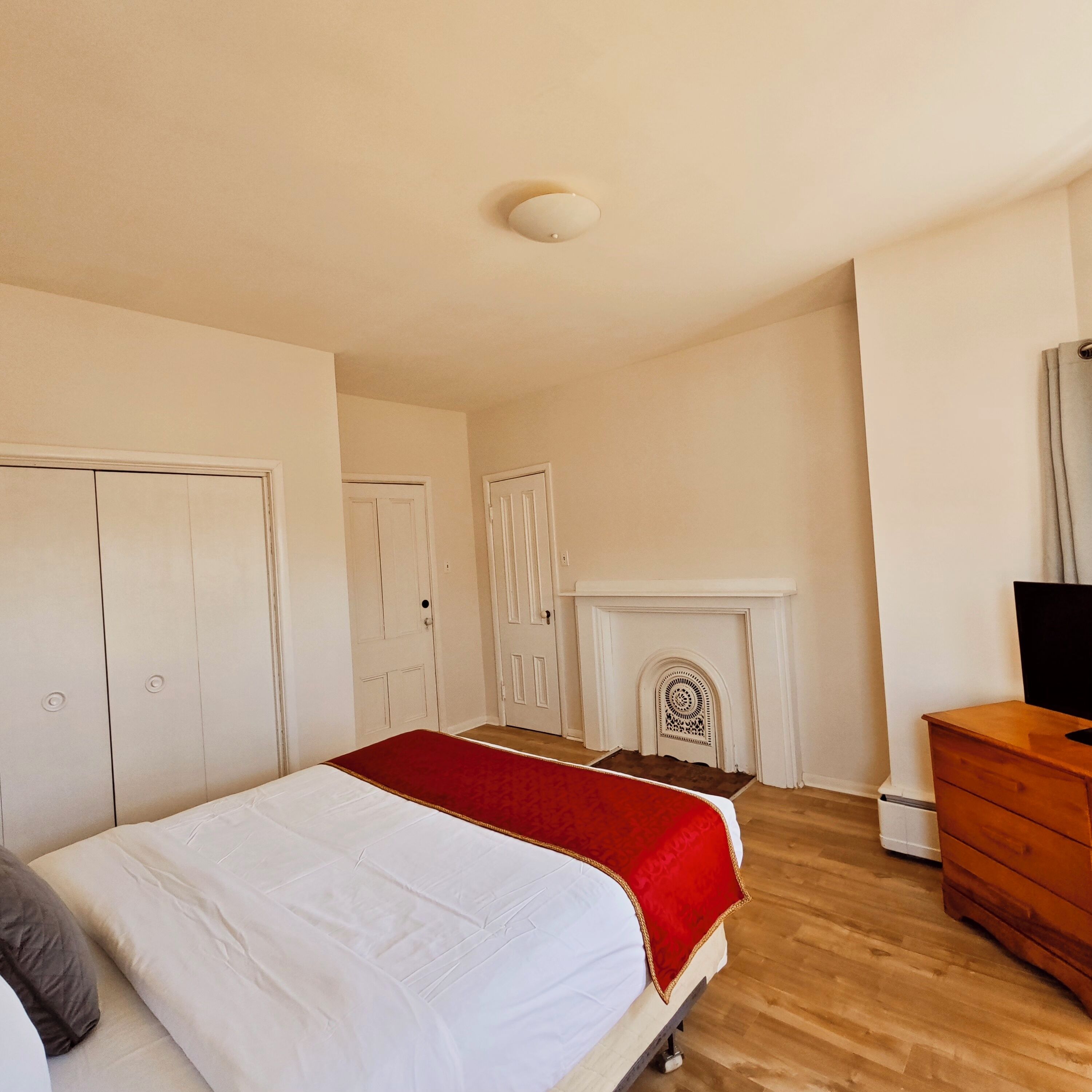 Ein Schlafzimmer mit einem Bett, einem Schminktisch, einem Kamin und zwei Türen.