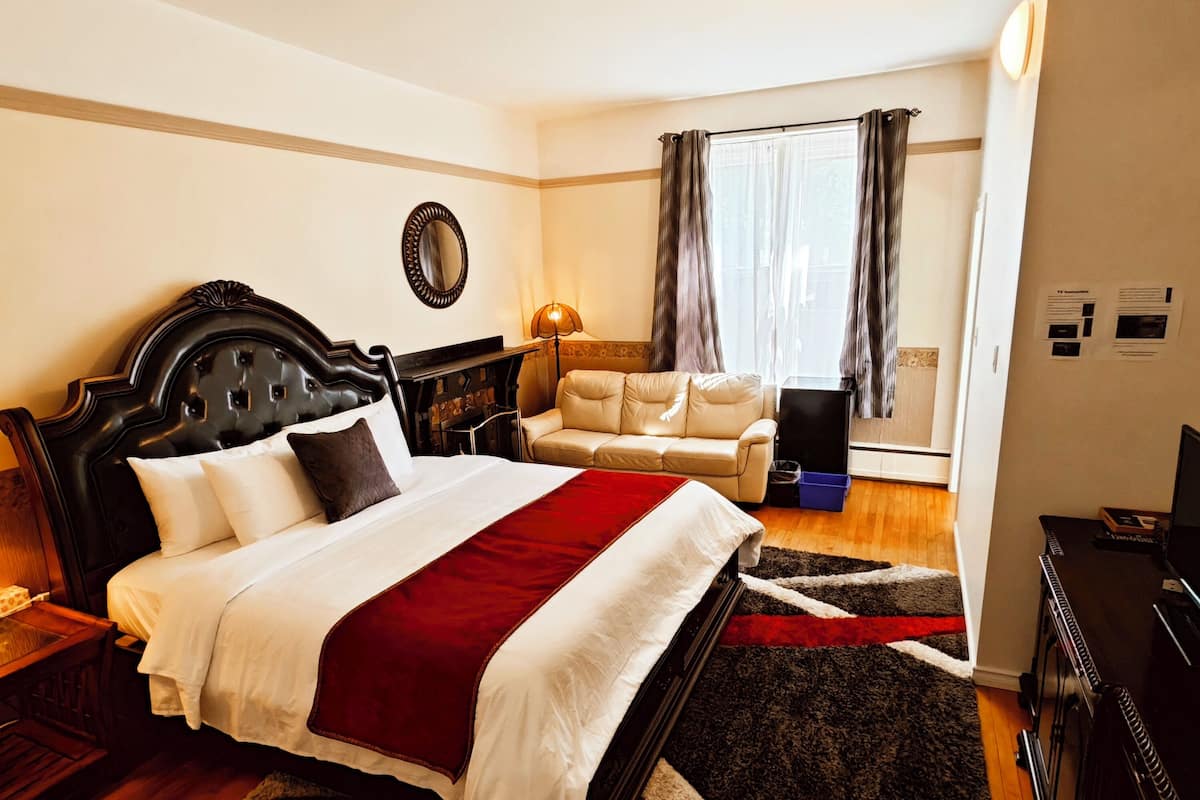 A hotel room with a large bed, a sofa, a desk, and a TV.
