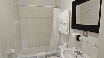 Un baño con bañera, inodoro, lavabo y espejo.