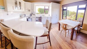 Una cucina moderna con mobili bianchi, un'isola grande e un'area pranzo con tavolo e sedie.