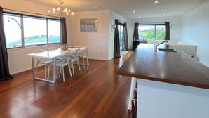 A spacious kitchen with a wooden countertop and a dining area with a table and chairs. - The King's Keep (Cable Bay)