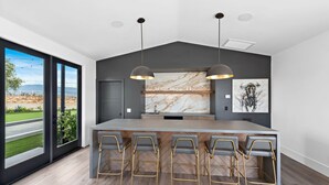 Een moderne keuken met een marmeren achterwand, een groot kookeiland met barkrukken en hanglampen.
