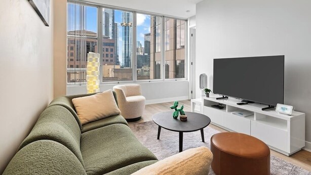 A modern living room with a large window, a flat-screen TV, a sofa, a chair, and a coffee table.