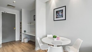 A modern dining area with a round table, white chairs, and a framed picture on the wall.
