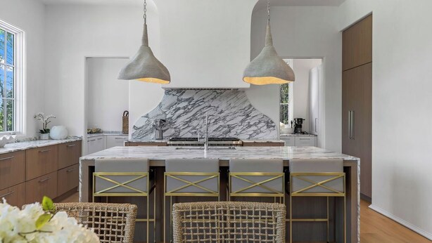 A modern kitchen with marble countertops, pendant lighting, and a central island with stools. - Oceanview Oasis: Luxury 6BR Home with Pool (Seagrove Beach)