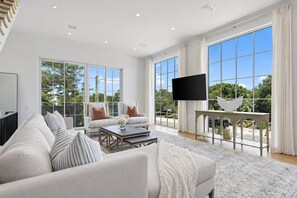 A spacious living room with a large sofa, two armchairs, a coffee table, and a flat-screen TV mounted on the wall. - Oceanview Oasis - 6BR Seagrove Beach Home on 30A - Private Pool - Sleeps 12 (Seagrove Beach)