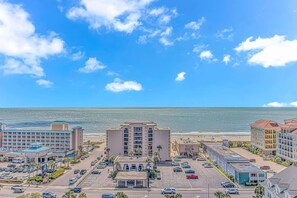 A coastal hotel area with multiple buildings, a parking lot, and a view of the ocean. - Holiday Towers 1503 (Myrtle Beach)