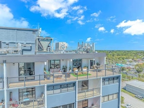 A multi-story building with balconies, outdoor seating, and a view of a cityscape. - Holiday Towers 1503 (Myrtle Beach)