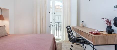 Ein Schlafzimmer mit Bett, Schreibtisch, Stuhl und Blick ins Freie.