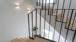 Una escalera moderna con barandilla de metal, peldaños de madera y una planta en maceta.