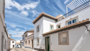 Una calle estrecha flanqueada por edificios blancos con techos de tejas y balcones.