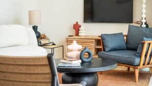 Una sala de estar moderna con un sofá, una mesa de centro y un televisor montado en la pared.