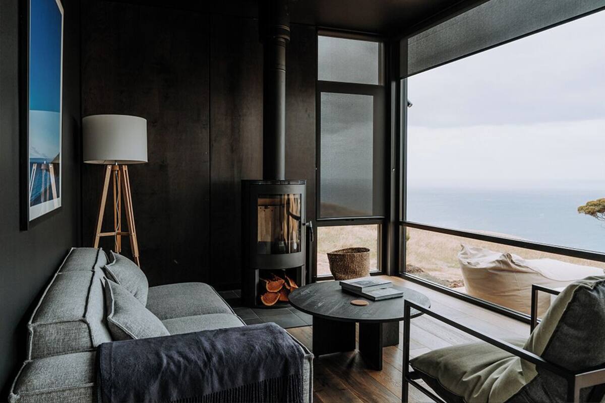 A cozy room with a sofa, a small table, a lamp, and a wood-burning stove.