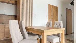 A modern dining area with a wooden table and four upholstered chairs. - Ursus Cosy Apartment #51 (Warszawa)