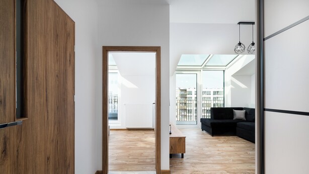 A modern living space with a wooden floor, a black sofa, and a glass ceiling.