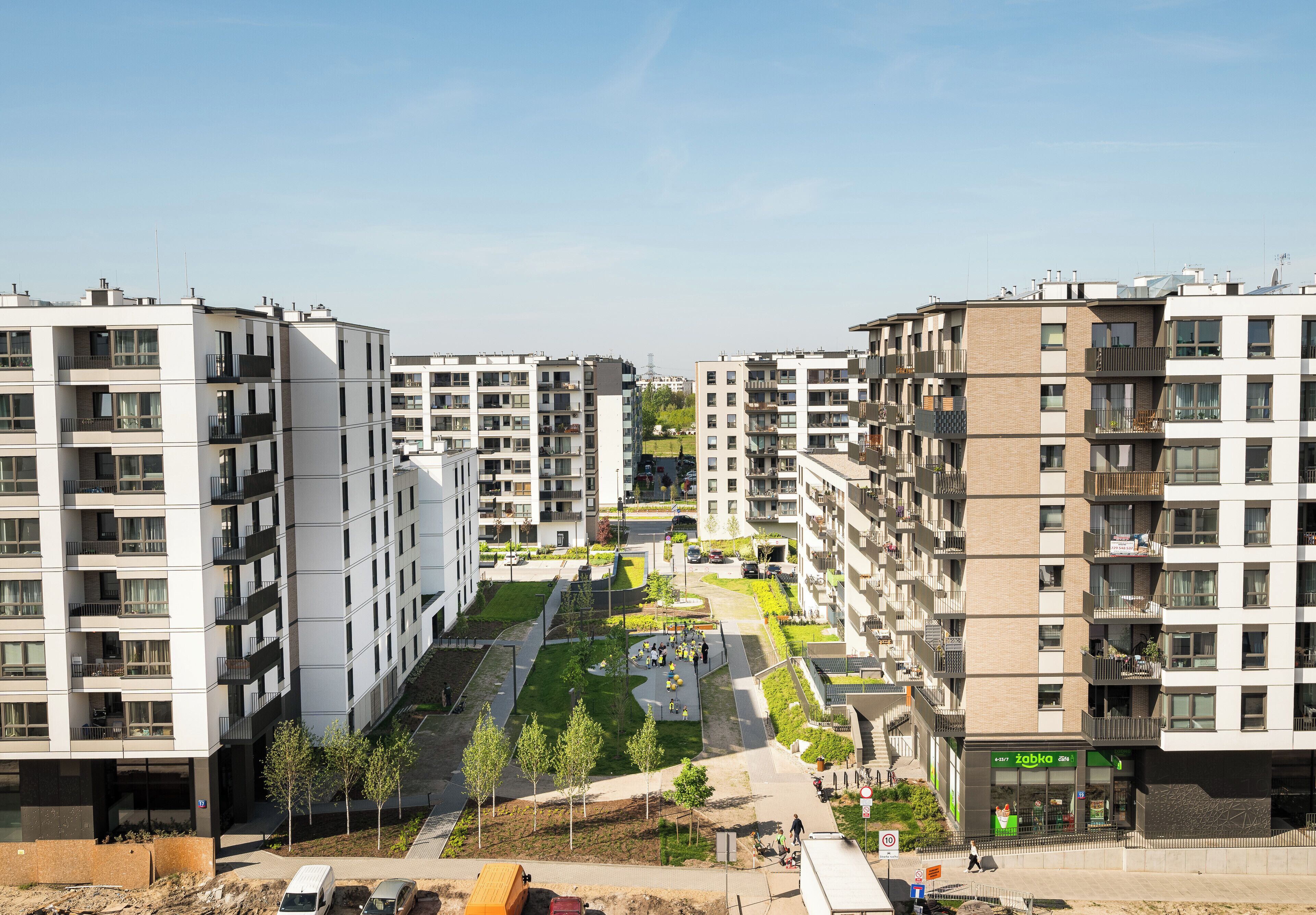 Un complejo de apartamentos moderno con varios pisos, balcones y un patio central con vegetación.