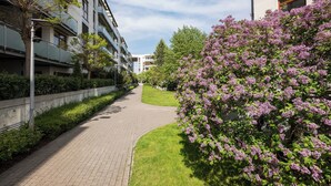 A pathway flanked by modern buildings and a flowering tree. - Las Kabacki Comfy Apartment (Warszawa)