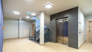 Un intérieur moderne avec un escalier, un ascenseur et un sol carrelé.
