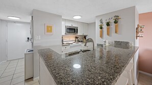 Eine moderne Küche mit Granit-Arbeitsplatten, Edelstahlgeräten und weißen Schränken.