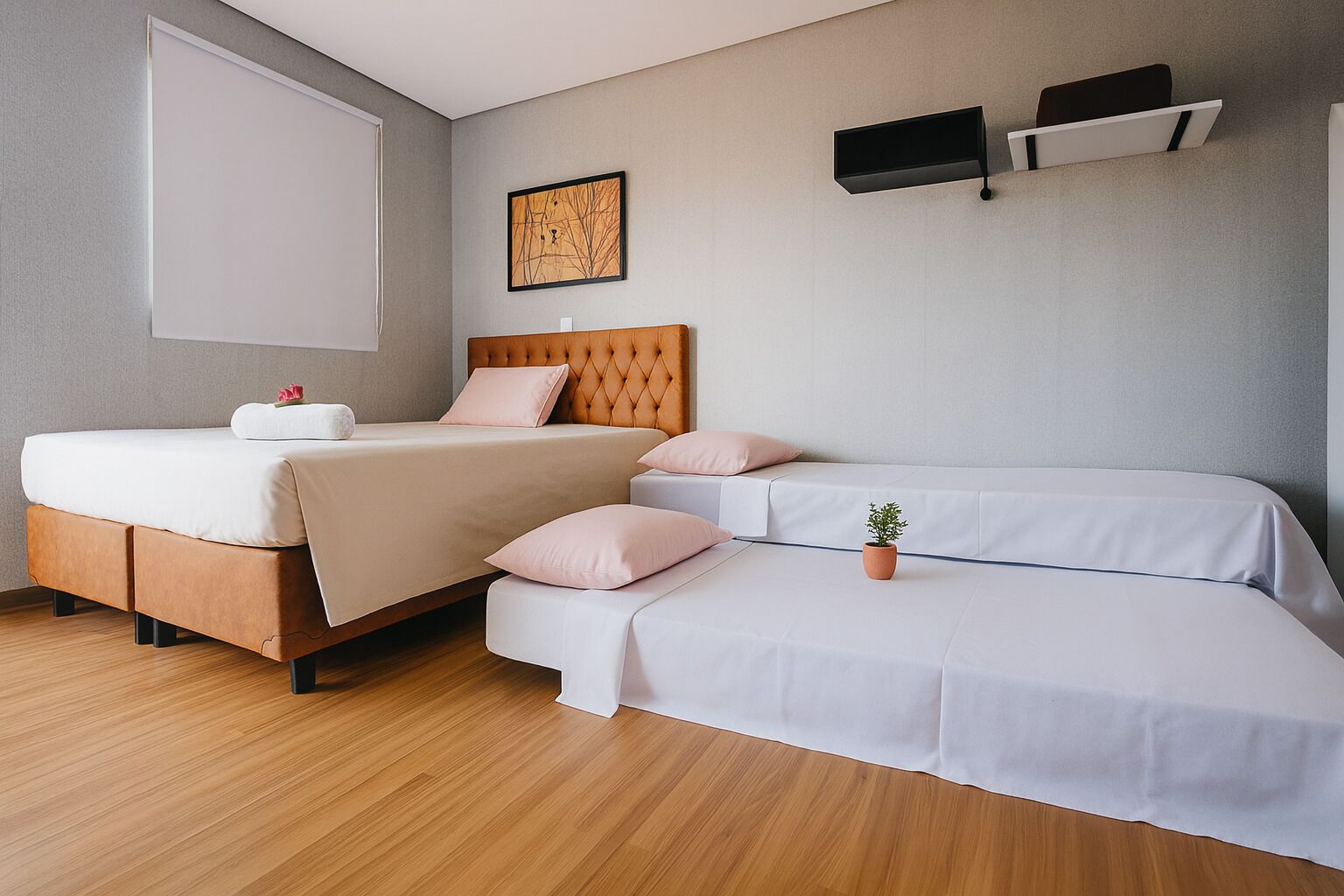 A modern bedroom with a large bed, a smaller sofa bed, and a bedside table with a plant.