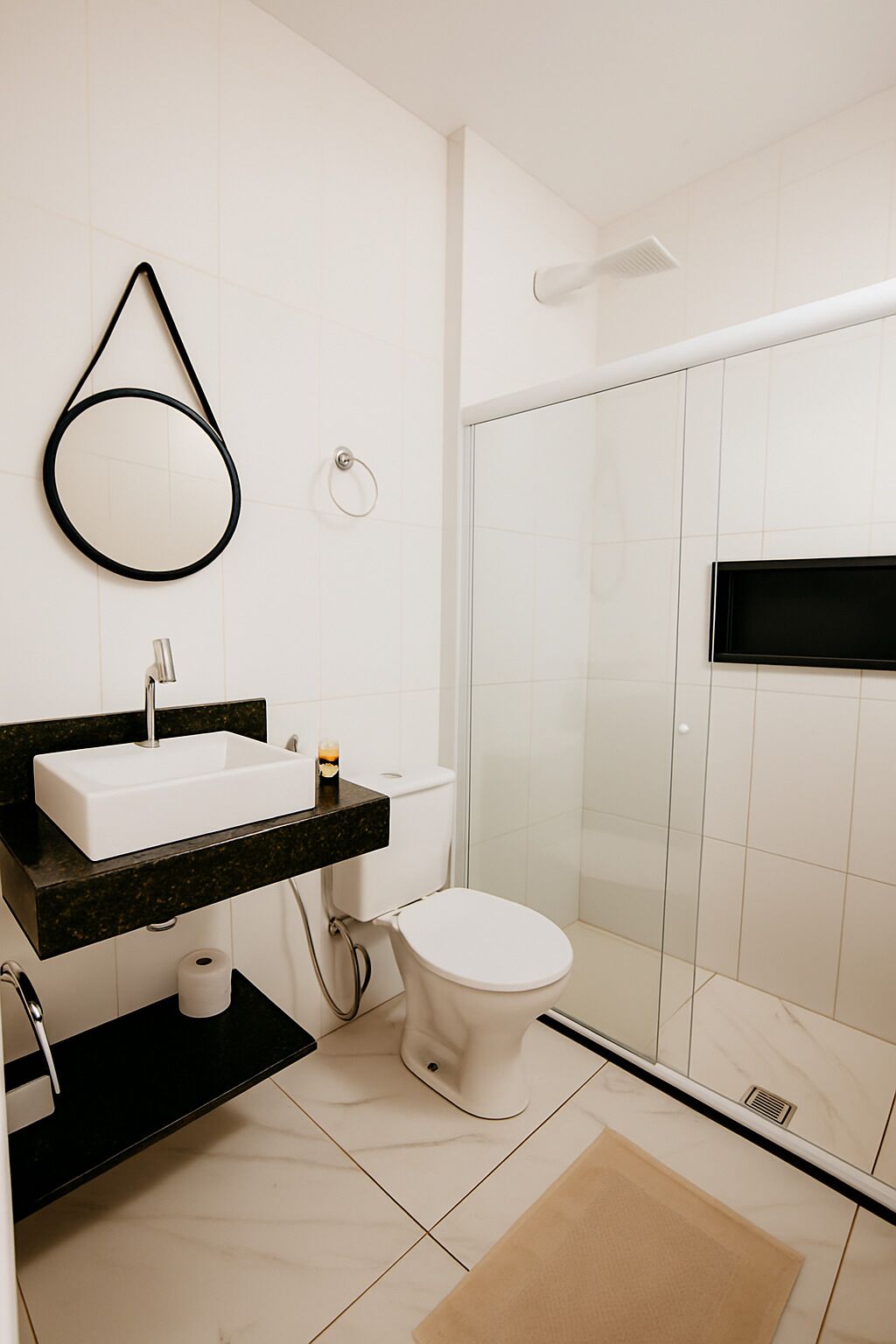 A modern bathroom with a white sink, black countertop, and a toilet.