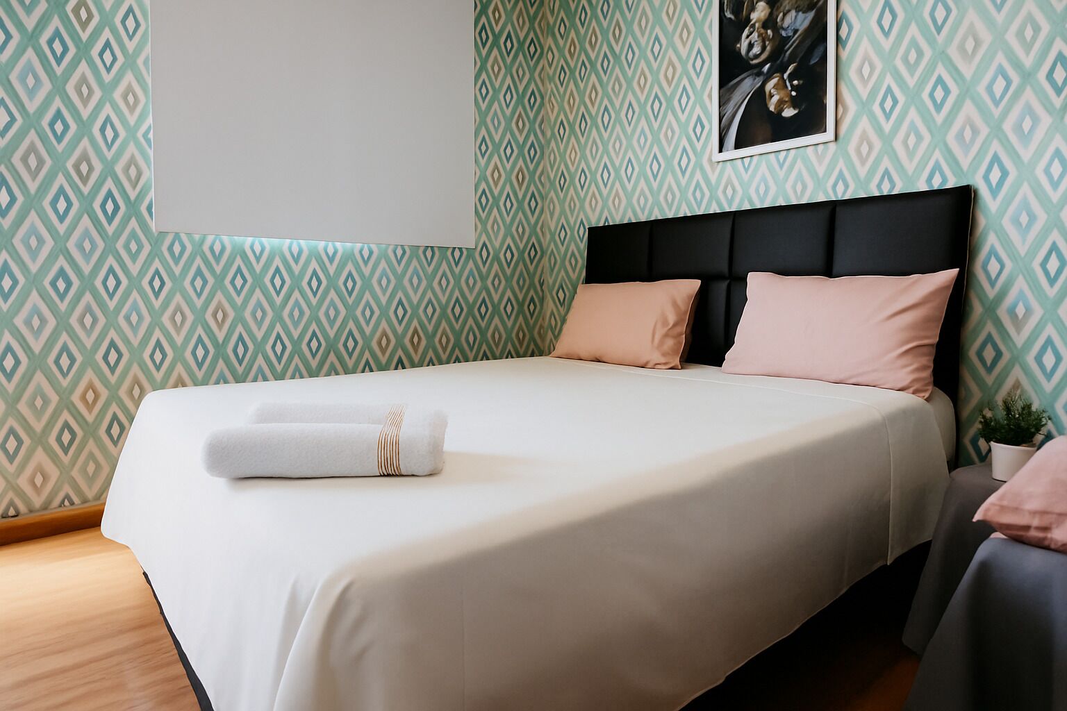 Una cama bien hecha con una colcha blanca y beige, un cabecero negro y dos almohadas.