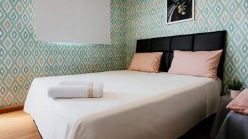 Una cama bien hecha con una colcha blanca y beige, un cabecero negro y dos almohadas.