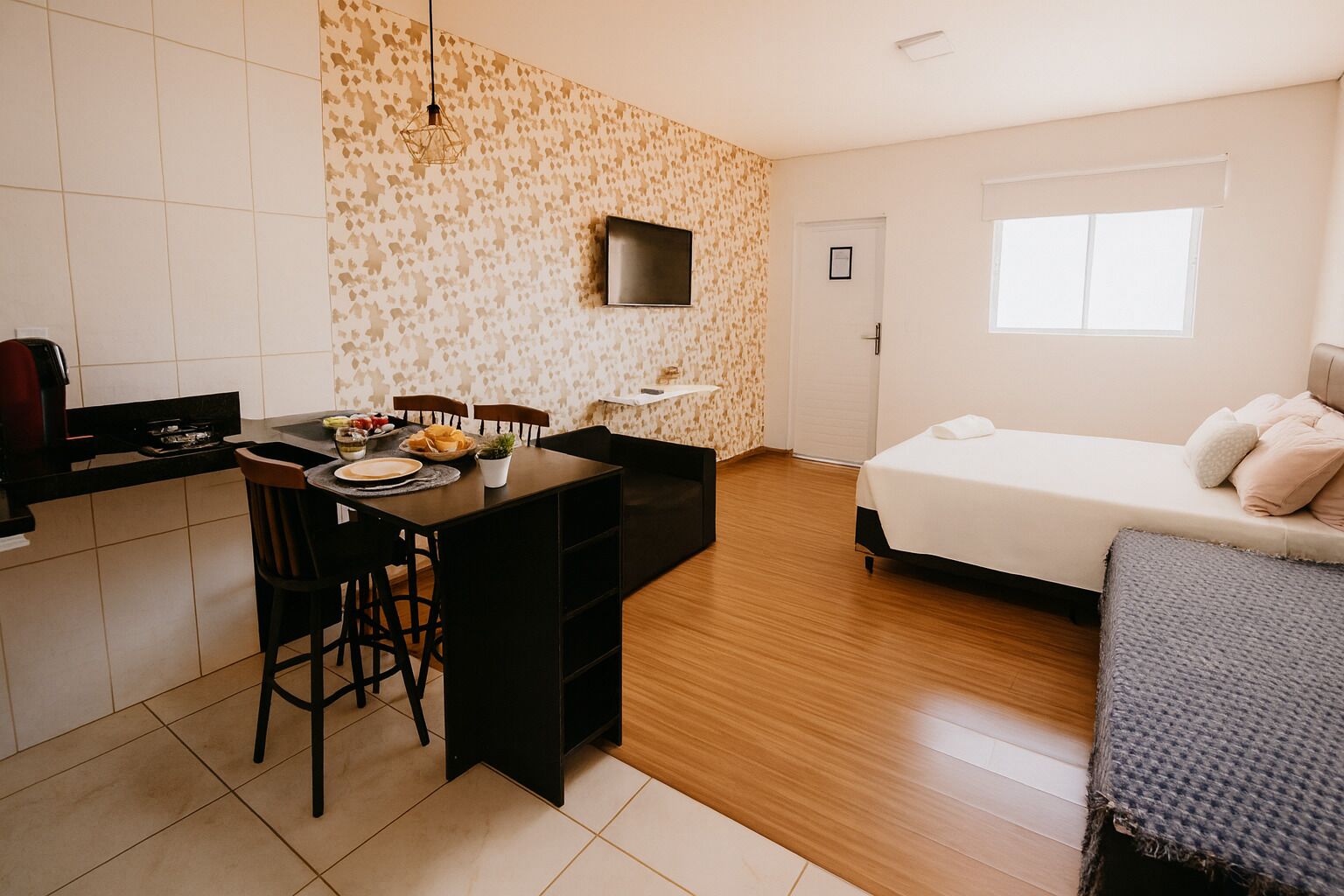 Una habitación compacta con kitchenette, comedor y cama.