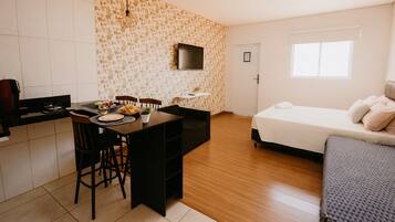 Una habitación compacta con kitchenette, comedor y cama.