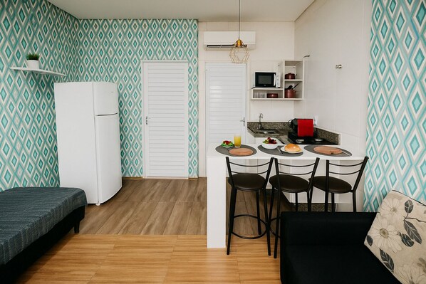 A compact kitchen with a dining area, white cabinets, a microwave, and a small refrigerator.