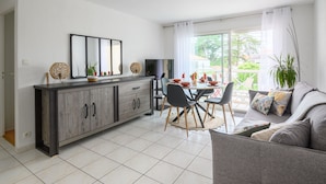 Eine moderne Küche mit Essbereich, ausgestattet mit einem grauen Schrank, einem Esstisch mit Stühlen und einem großen Fenster mit Vorhängen.