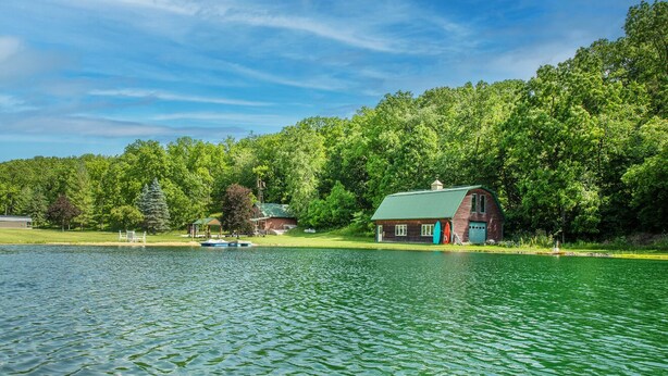 A lakeside cabin with a green roof, surrounded by dense forest. - Modern Cottage Cabin, private area with pond, fishing nearby, swimming and more  (McGregor)