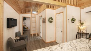 A hotel room with a wooden ceiling, a marble countertop, a TV mounted on the wall, and a small table with a lamp. - Modern Cottage Cabin, private area with pond, fishing nearby, swimming and more  (McGregor)