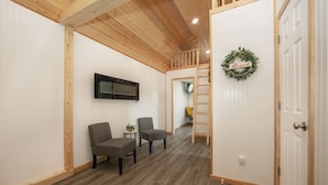 A room with a wooden ceiling, a white door with a 'blessed' sign, and two grey chairs. - Modern Cottage Cabin, private area with pond, fishing nearby, swimming and more  (McGregor)