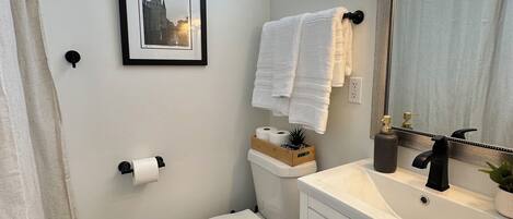 A bathroom with a toilet, sink, and a framed picture on the wall.