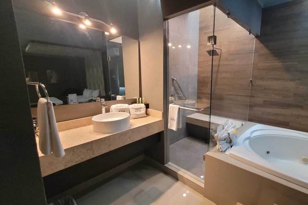 A modern bathroom with a large bathtub, a round sink, and a glass shower enclosure.