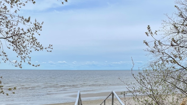 A metal staircase leading to a beach with a view of the sea. - Cabin in South Beach - Steps from the beach (Gimli)
