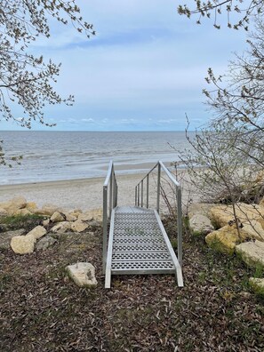 A metal staircase leading to a beach with a view of the sea. - Cabin in South Beach - Steps from the beach (Gimli)