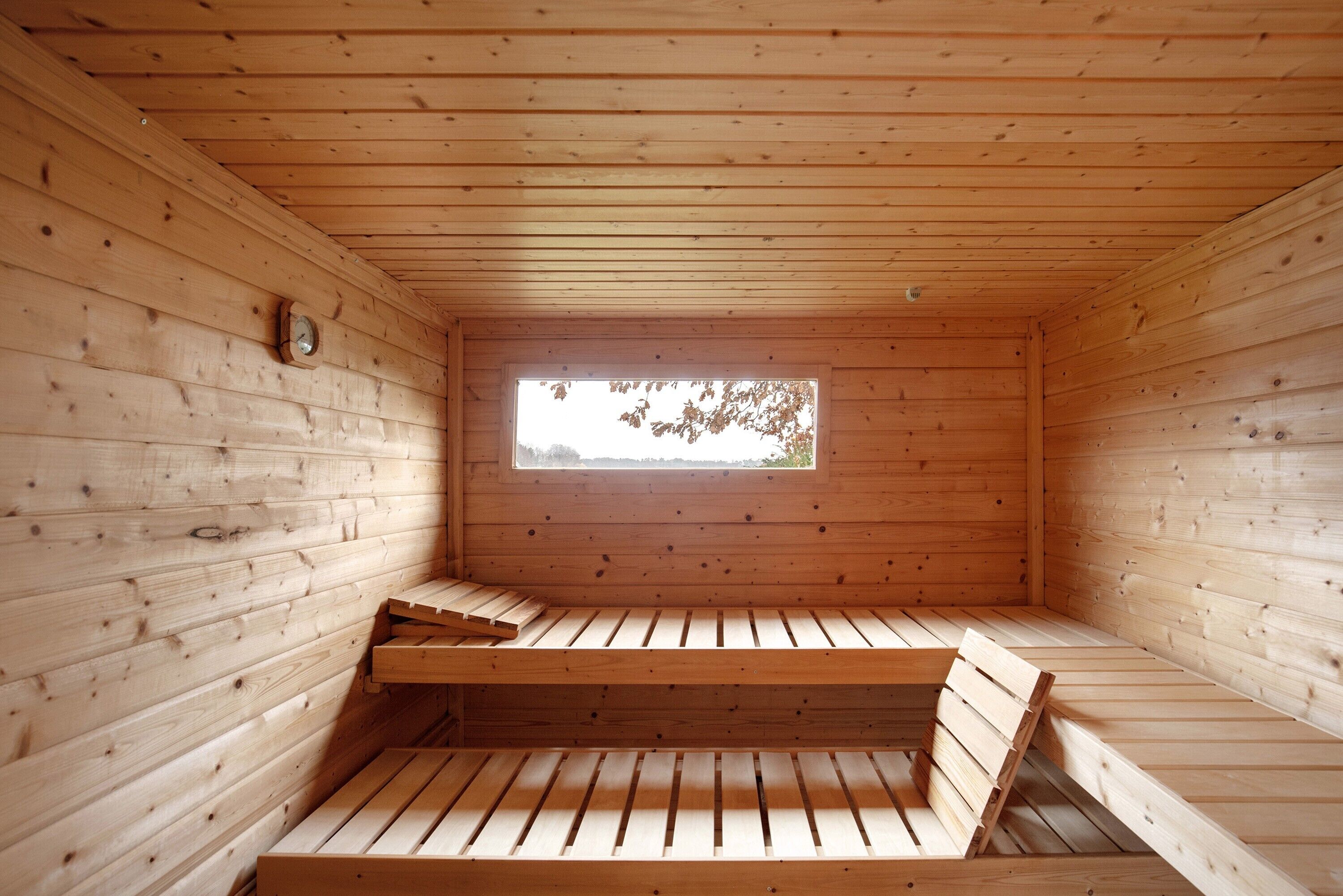 Une pièce dans une cabane en bois, avec une fen être, un banc et une petite table.