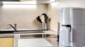 Eine Küche mit einer Edelstahl-Spüle, einer Kaffeemaschine und einem Besteckhalter.