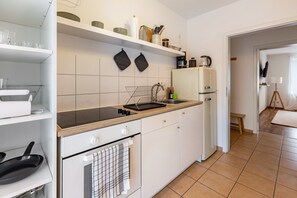 Una cucina moderna con mobili bianchi, un piano di lavoro nero, forno integrato, lavello e frigorifero.