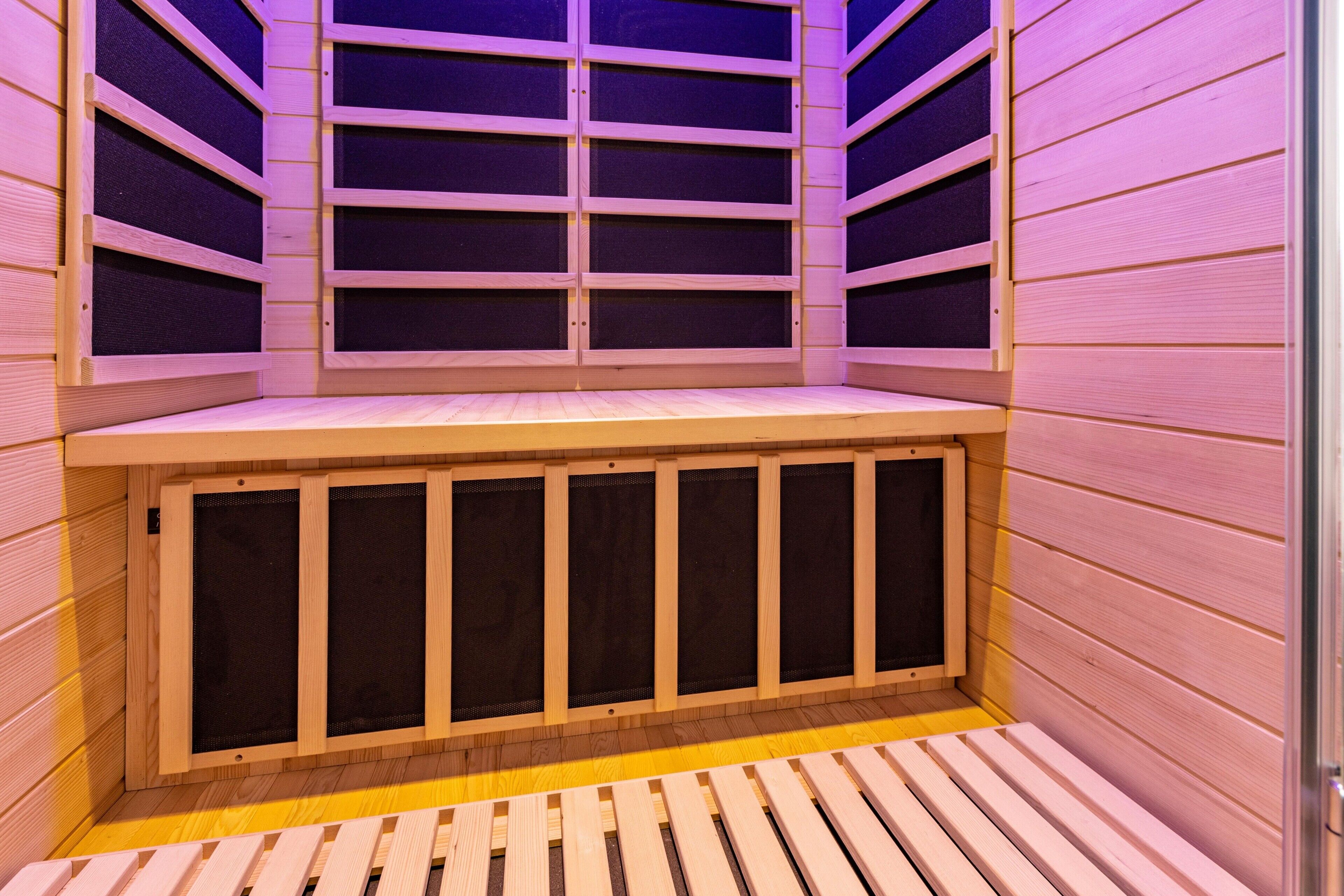 Una sauna con bancos y paredes de madera, un banco en el centro y otro en la parte inferior.