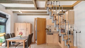 Una cocina moderna con armarios de madera, lavavajillas integrado y una escalera original con barandillas de metal.